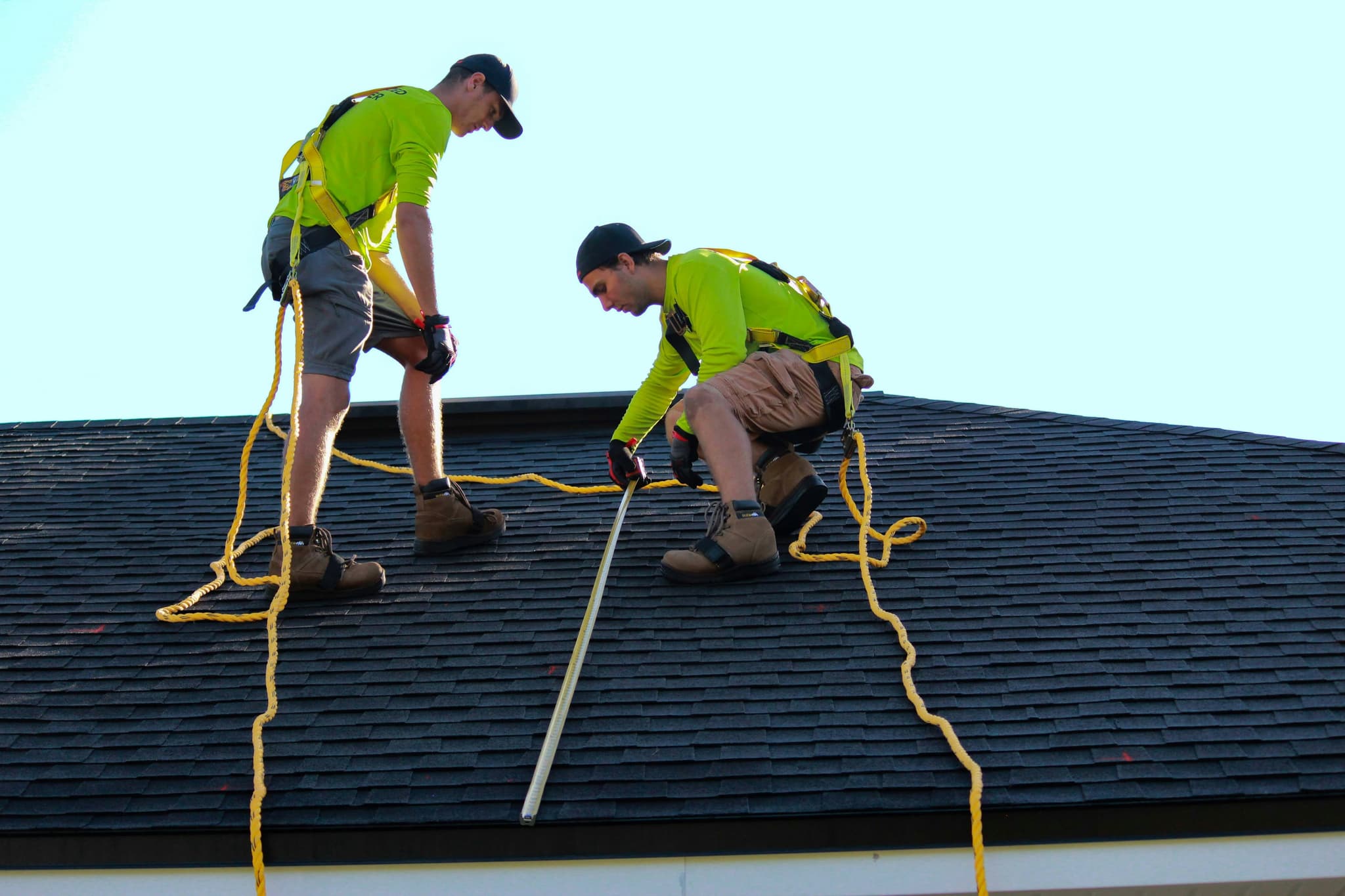 Workers installing shingles on a steep roof