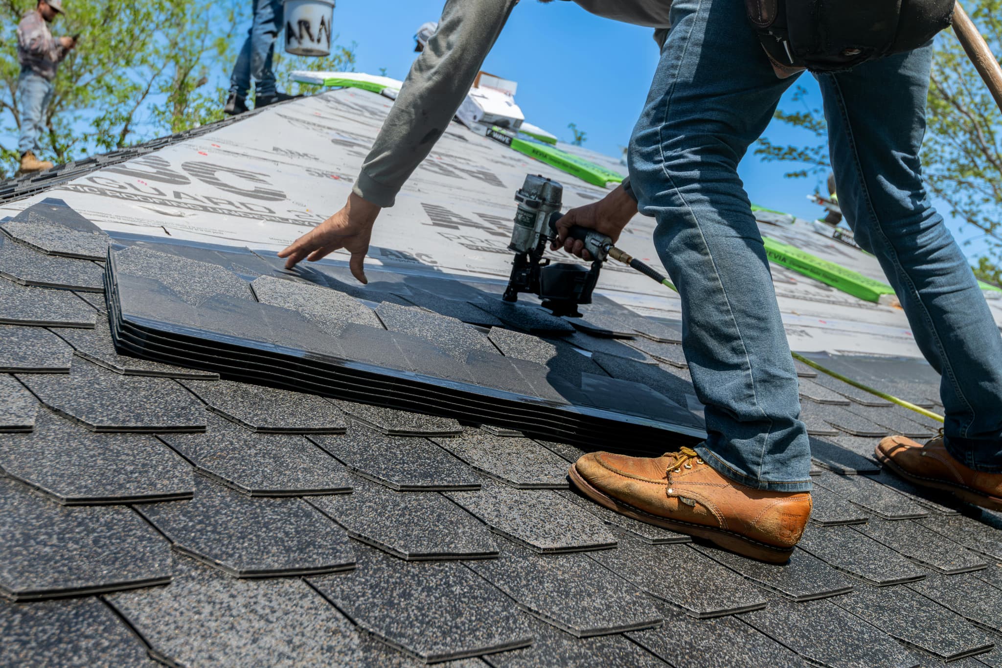 Roofers repairing shingles on a house roof